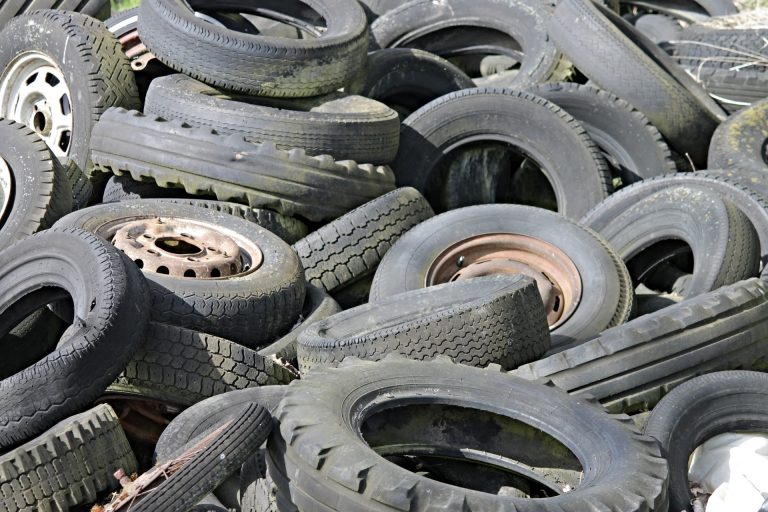 Sterta czarnych, zużytych opon z widocznymi bieżnikami i metalowymi obręczami do recyklingu opon