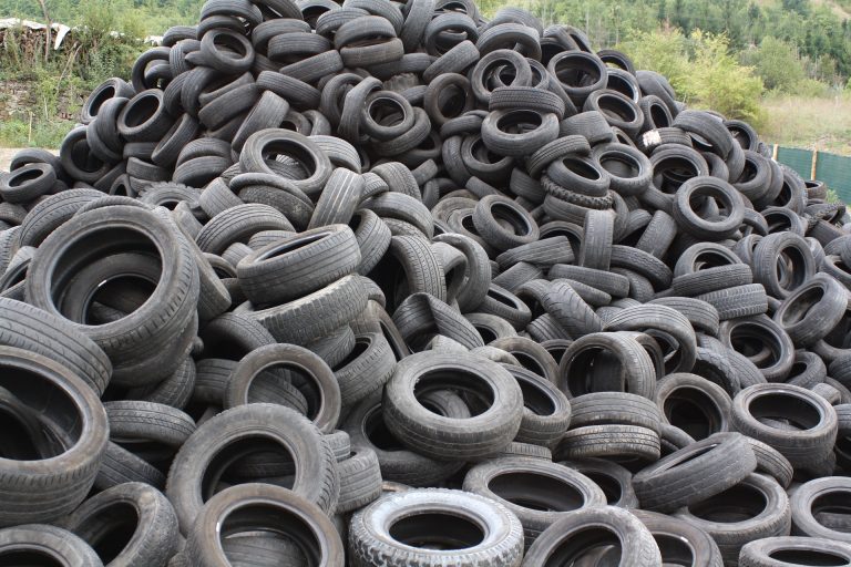 Gęsty stos czarnych i szarych opon samochodowych z widocznym bieżnikiem, wykorzystywanych w recyklingu przez Esbud Firma Recyklingowa